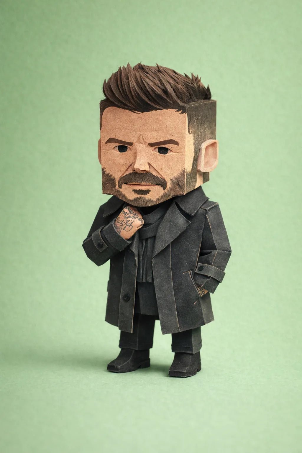 Cube-headed cardboard paper toy character on colorful studio background, showing photo-to-figure style with clean negative space: Beckham