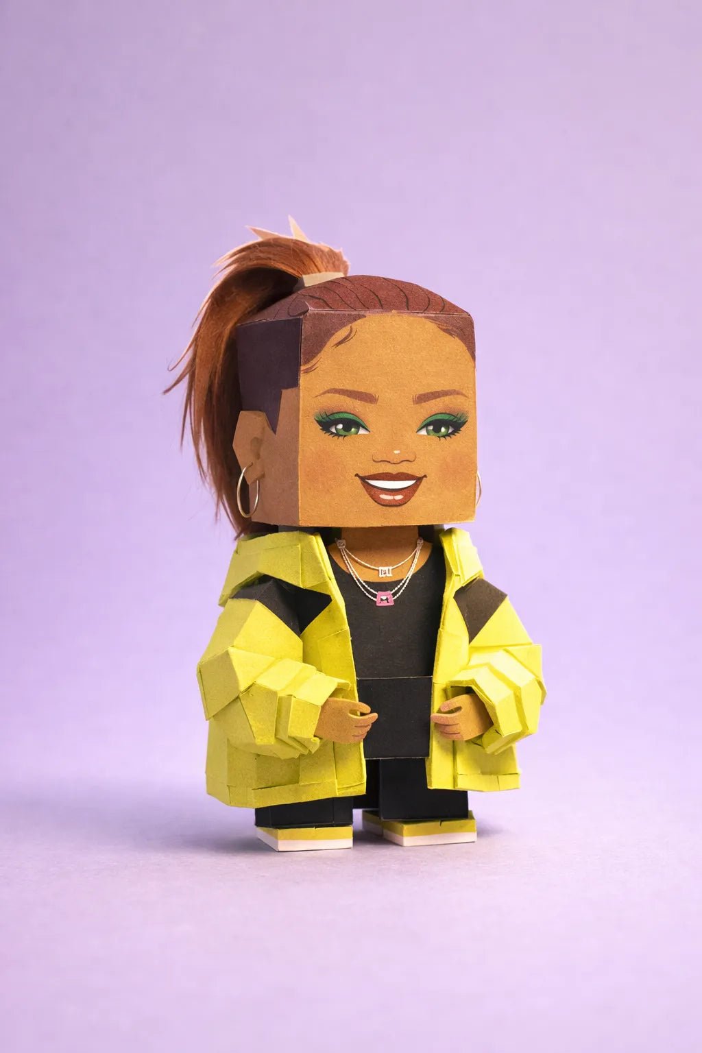 Cube-headed cardboard paper toy character on colorful studio background, showing photo-to-figure style with clean negative space: Rihanna