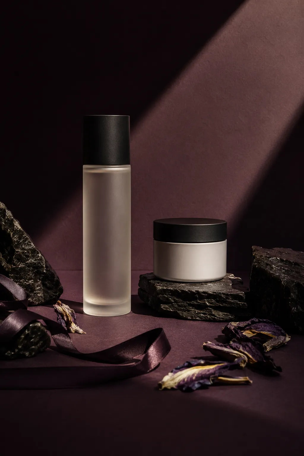 Example output from the Editorial Beauty Product Photos ChatGPT prompt: a luxury editorial skincare product photo with dramatic sunlight, sculptural shadows and a cream tube and jar styled with textured stone in cool tones.
