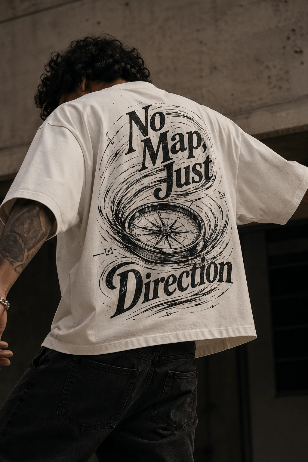 Example output from the Heritage Back Print Tee Designs ChatGPT prompt: a cream oversized tee with a No Map Just Direction back print featuring a weathered compass rose.