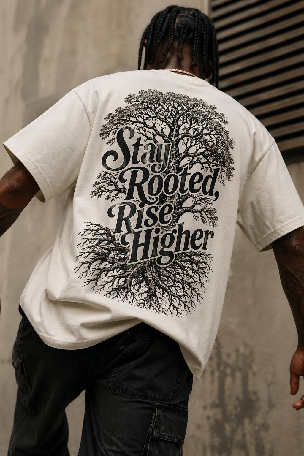 Example output from the Heritage Back Print Tee Designs ChatGPT prompt: a cream oversized tee with a Stay Rooted Rise Higher back print featuring an engraved tree and root system.