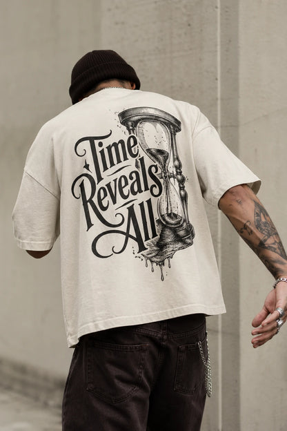 Example output from the Heritage Back Print Tee Designs ChatGPT prompt: a cream oversized tee with a Time Reveals All heritage back print, shot from behind against a concrete backdrop.